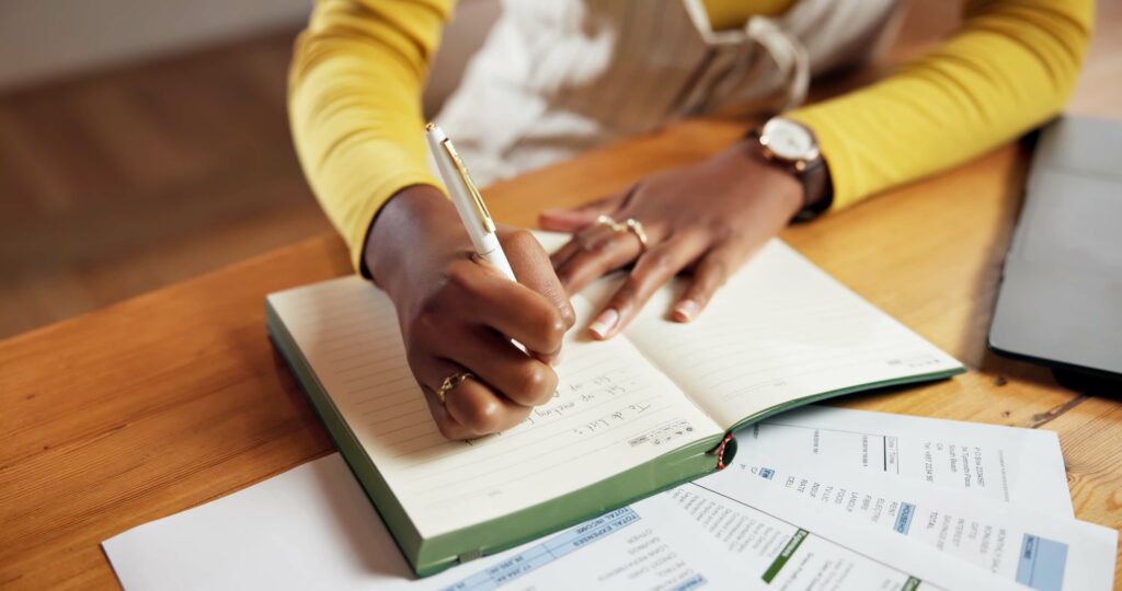 woman holding pen, writing on a notebook